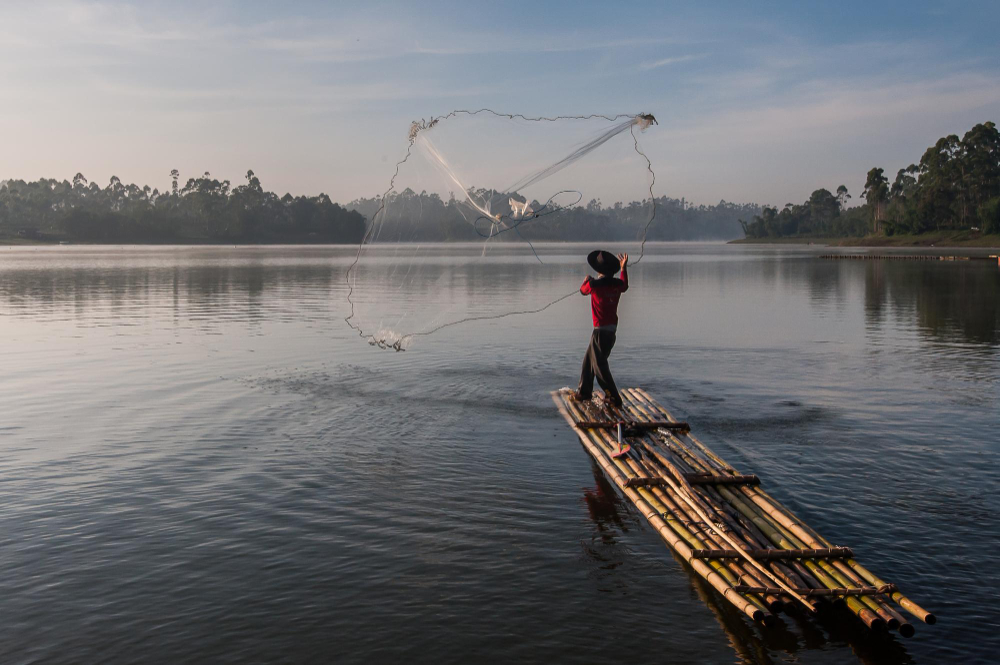man fishing in river with a bamboo traps in streams